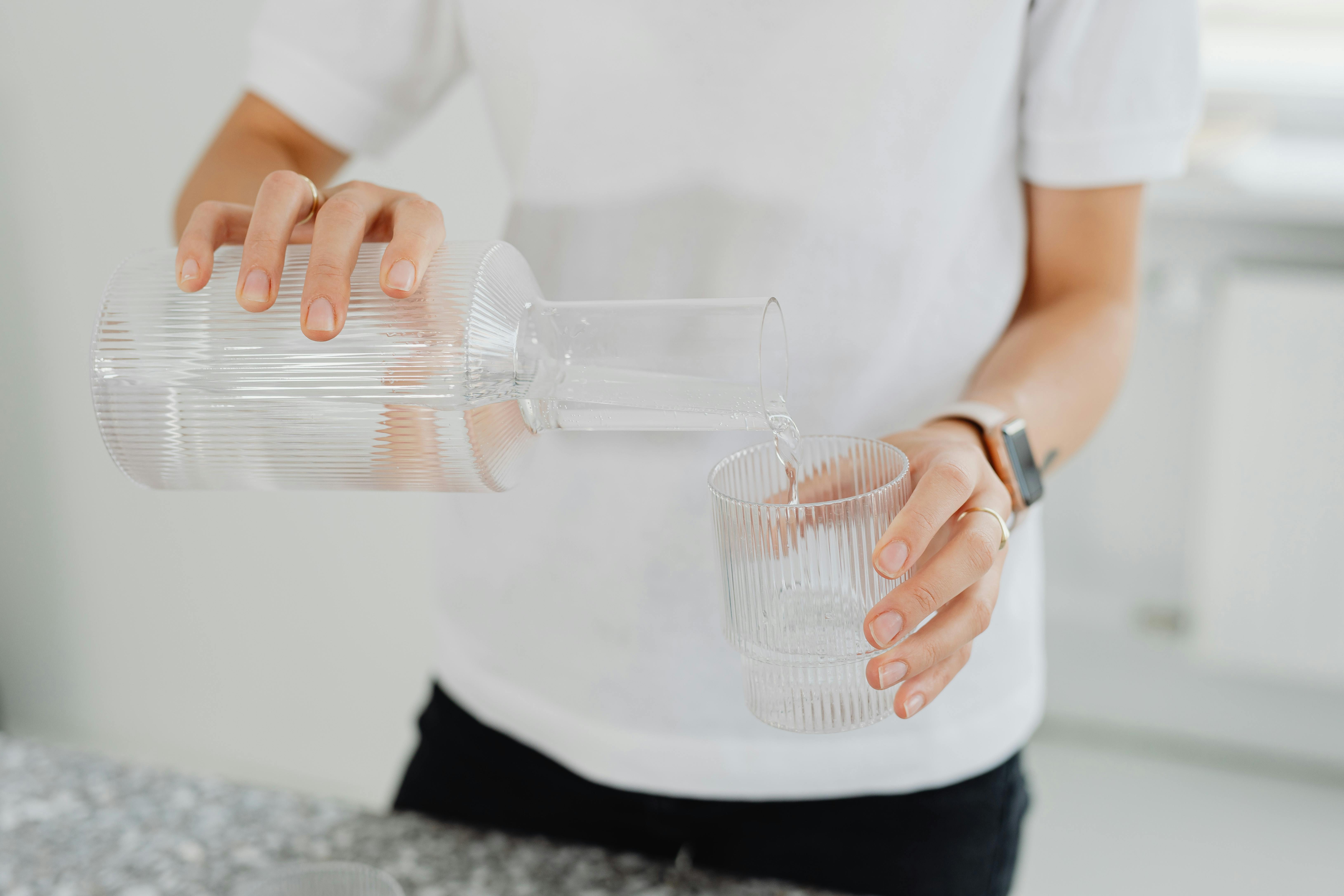 Pouring water into a glass on a bright table